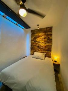 1 dormitorio con cama blanca y pared de ladrillo en Brand new Modern Casa w/ Pool 7 mins from Centro, en Mérida