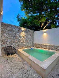 una piscina con una silla junto a una pared de piedra en Brand new Modern Casa w/ Pool 7 mins from Centro, en Mérida