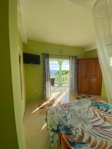 a bedroom with a bed and a view of the ocean at Greenhouse on the Hill, Sea View Studio Apartment in Laborie