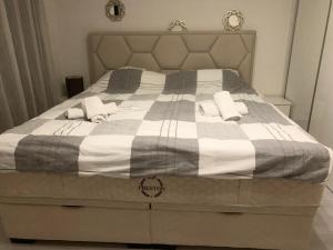 ein Bett mit einer grauen und weißen Decke und Kissen in der Unterkunft Colors Apartment Sarajevo in Sarajevo
