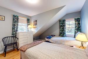 un dormitorio en el ático con 2 camas y una silla en Green Mountain Retreat, en Sunderland