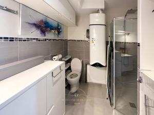 a white bathroom with a toilet and a shower at L'Oasis des Clayes in Les Clayes-sous-Bois