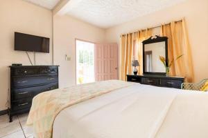 a bedroom with a bed and a dresser and a mirror at Shaw Park Gem Apt 12A in Ocho Rios