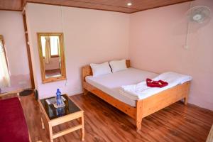 a small bedroom with a bed and a mirror at Rio De Vallis Eco Resort in Kalimpong