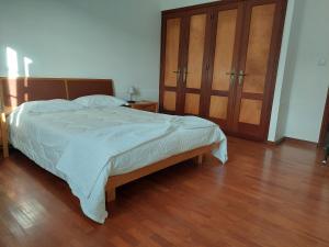 a bedroom with a large bed and wooden floors at Casa da Adega in Ribeira Chã