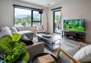 a living room with a couch and a tv at Revy's Peak Condo - Hot Tub with View in Revelstoke