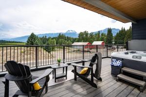 a patio with chairs and a hot tub on a deck at Revy's Peak Condo - Hot Tub with View in Revelstoke