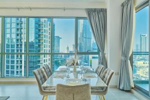 une salle à manger avec une table, des chaises et une grande fenêtre dans l'établissement Burj Khalifa Front view & Fountain view Island Paradise 2BR Luxury Apartment Burj residences Golden Homes, à Dubaï