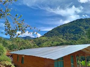 un edificio con techo de metal con montañas al fondo en Cabaña Paraíso Verde, en Providencia