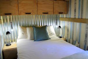 łóżko z białą pościelą i niebieską poduszką w obiekcie Ndlovu Tiny Home Dinokeng w mieście Klipdrift