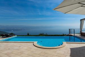 een zwembad met een parasol en uitzicht op het water bij Villa Marone in Opatija