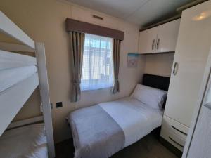 a small bedroom with two bunk beds and a window at Golden Palm Resort - The Ascot - Coastal Caravan Breaks in Chapel Saint Leonards