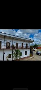 a white building with a balcony and a parking lot at Bless in Tela