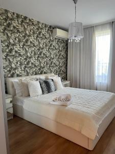 1 dormitorio con 1 cama blanca grande y pared en Apartment Stella, en Varna