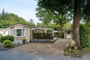 una casa con un árbol y una entrada de ladrillo en Chalet Jagershut K 6 op park Mooi Oavelt., en Havelte
