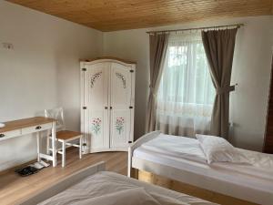 1 dormitorio con 2 camas, escritorio y ventana en Casa Piscul Verde Vladeni, en Vlădeni