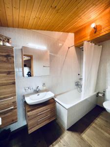 a bathroom with a tub and a sink and a bath tubermottermott at Panorama Hak - CharmingStay in Flumserberg