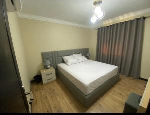 een slaapkamer met een wit bed en een nachtkastje bij Ocean Blue Luxury serviced Hotel Apartments in Caïro