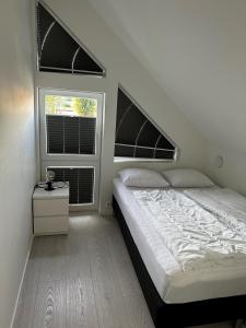 a bedroom with a bed and two windows at Årossanden hytte nr 4 O in Søgne
