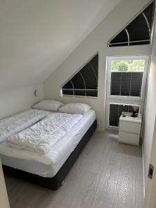 1 dormitorio blanco con 1 cama y 2 ventanas en Årossanden hytte nr 4 O, en Søgne