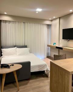 - une chambre avec un lit, une table et une télévision dans l'établissement Golden Gramado Resort, à Gramado