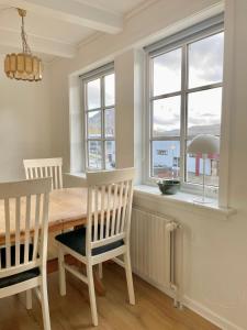 uma sala de jantar com mesa, cadeiras e janelas em House in Fuglafjørður em Fuglafjørður