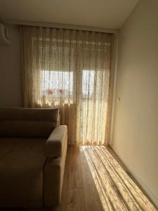 een woonkamer met een bank en een groot raam bij Apartmani IMPERIAL 2 in Novi Pazar