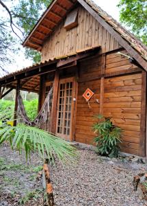 a wooden cabin with a net in front of it at Chalés do Atlântico Sc in Itapoa
