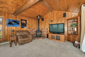 a living room with a flat screen tv and a chair at Kenai Vacation Rental with Volcano and Glacier Views! in Kenai