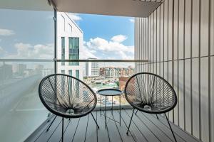 two chairs on a balcony with a view of a city at Wyspa Spichrzów Residence in Gdańsk