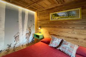 una camera con un letto rosso e una parete con un dipinto a muro di cervo di Hotel Belvedere a Cogne