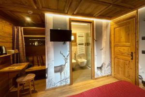 1 dormitorio con baño y ventana con ciervo. en Hotel Belvedere, en Cogne