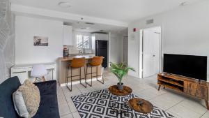 ein Wohnzimmer mit einem Sofa und einem TV sowie eine Küche in der Unterkunft Apartment 1 1 near Ballpark and Hospitals Airport in Miami