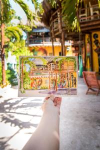 a person holding up a picture of a temple at Tribu Hostel in Holbox Island
