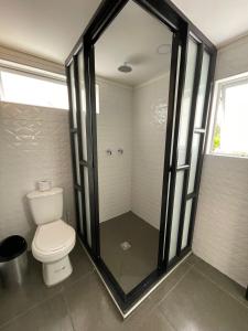a bathroom with a toilet and a glass shower at Tiny House Tauramena in Tauramena