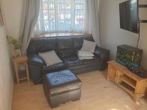 a living room with a black leather couch and a fishtank at Harry Potter theme Double room in shared house in Garston