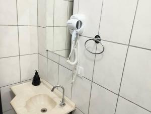 uma casa de banho com secador de cabelo na parede ao lado de um lavatório em Estrela da Manhã Pousada - Centro de Águas - próximo ao Thermas em Águas de São Pedro