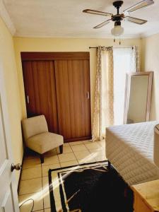 1 dormitorio con 1 cama, 1 silla y 1 ventana en apartamento equipado en Amatitlán