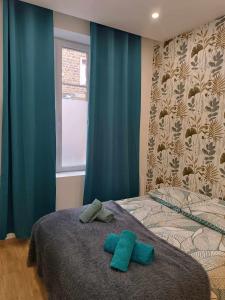 1 dormitorio con 1 cama con 2 almohadas verdes en Logement cosy hypercentre, en Coutances