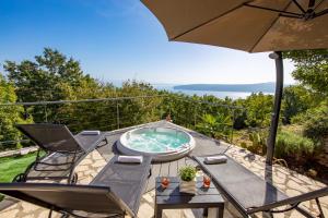 a patio with a hot tub and chairs and an umbrella at Villa Surina in Mošćenice