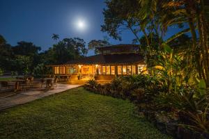 a house lit up at night with the moon behind it at Itamambuca Eco Resort in Ubatuba