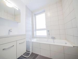 La salle de bains blanche est pourvue d'une baignoire et d'une fenêtre. dans l'établissement Les Terrasses Du Lac, à Vielsalm