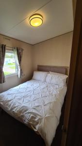 a large white bed in a room with a window at 8 Berth Luxury Caravan Butlins Holiday Village Skegness in Skegness