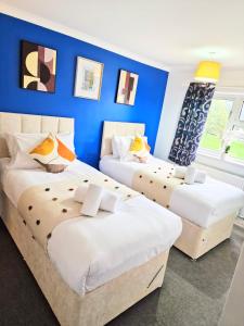 Duas camas num quarto com uma parede azul em 1 Bed Central Serviced Accommodation with Balcony in Stevenage Free WIFI by Stay Local Home Welcome Contractors Business Travellers Families em Stevenage