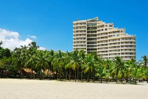 サンタ・マルタにあるHotel Irotama del Solの浜辺のヤシの木が立ち並ぶ高層ビル