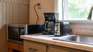 a kitchen counter with a coffee maker and a microwave at Cobblestone Cottages in Sharbot Lake