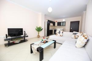 uma sala de estar com um sofá branco e uma televisão em Apartment oslo 4 em Vlorë