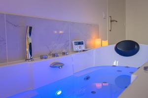 ein Bad mit einer blauen Badewanne in einem Zimmer in der Unterkunft Cinéma & Jacuzzi aux Étoiles - CasaBianca Suite in Saint-Étienne