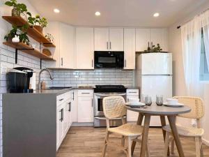 una cucina con armadi bianchi e tavolo con sedie di The Cozy Oasis - A Renovated and Modern Studio near LAX + SoFi + Beaches + Freeway a Lawndale