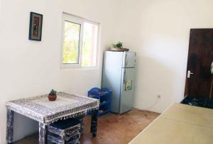 eine Küche mit einem Kühlschrank, einem Tisch und einem Fenster in der Unterkunft Manasha Apartment 1 in Watamu